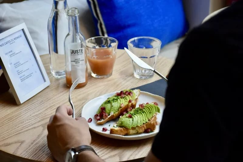 Croissant salé garni d'avocat tranché, graines de grenade et ciboulette, servi dans une assiette blanche