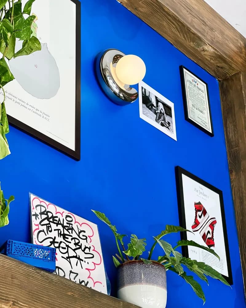 Mur bleu Klein du café orné de cadres : Petit Prince, affiche Air Jordan et appliques chromées